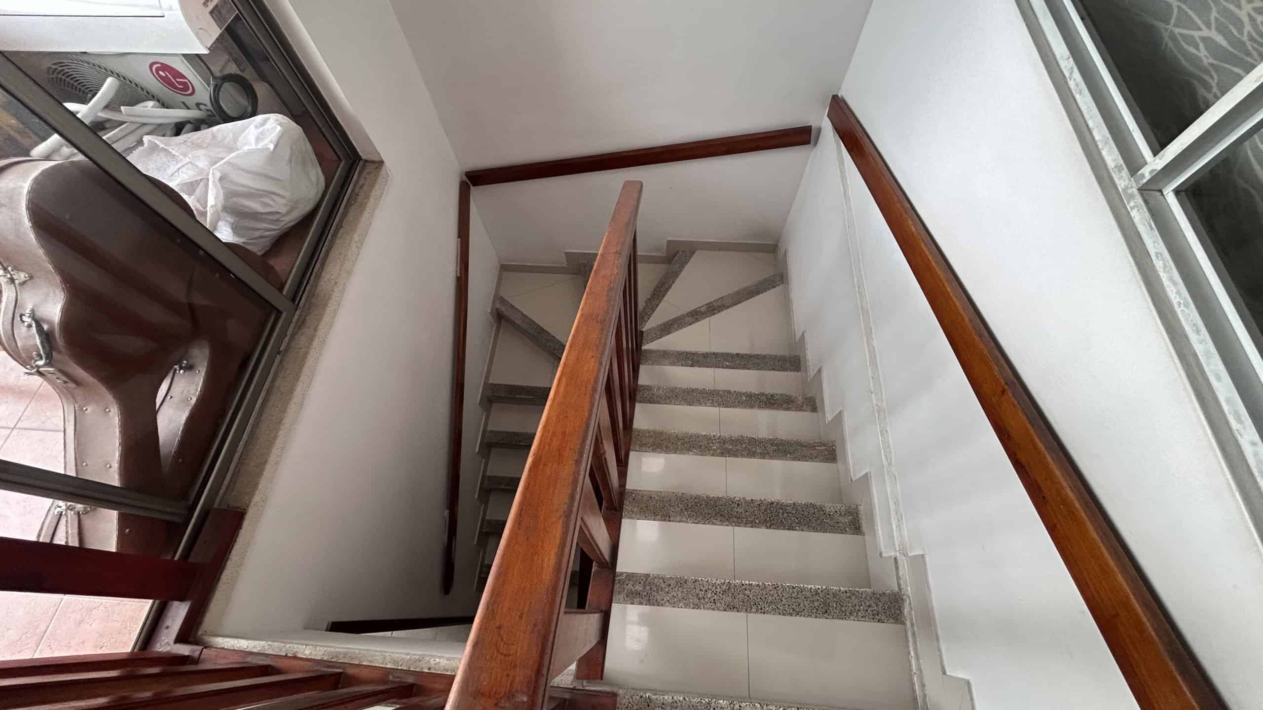 Escalera interior de la casa en Estancia del Vergel, Ibagué, con barandales de madera y pisos de cer.